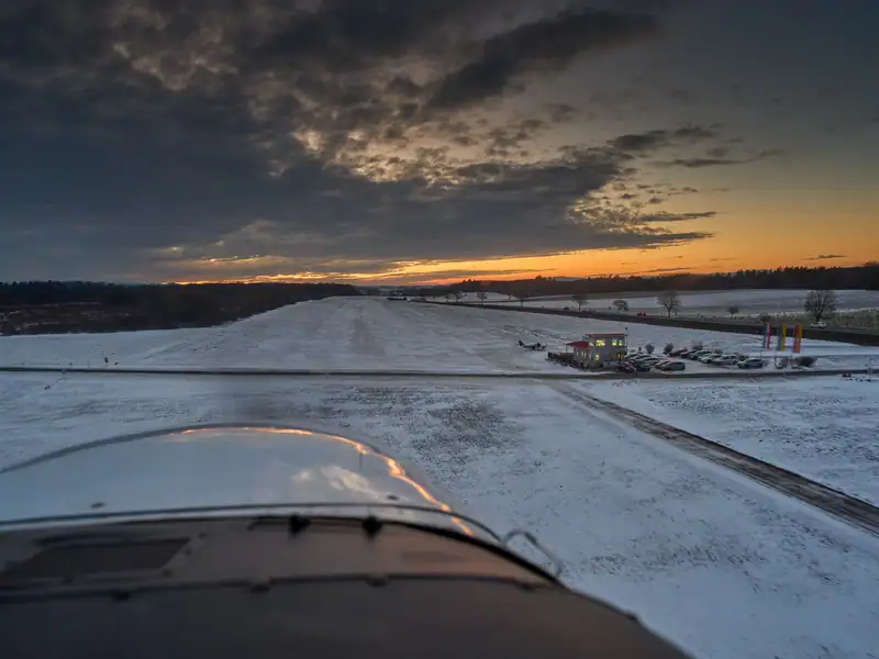 Verschneiter Flugplatz Völtendorf in der Abenddämmerung, Blick über die Motorhaube auf Piste und Vereinsheim