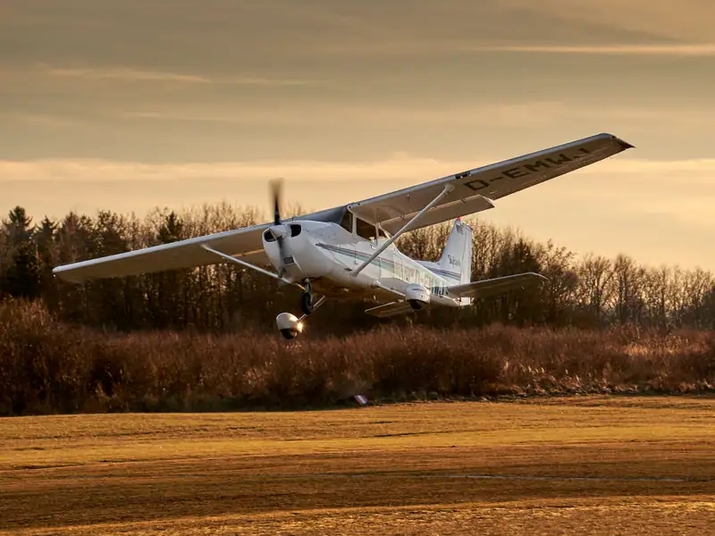 Cessna 172 Skyhawk im tiefen Anflug über die Graspiste im Abendlicht