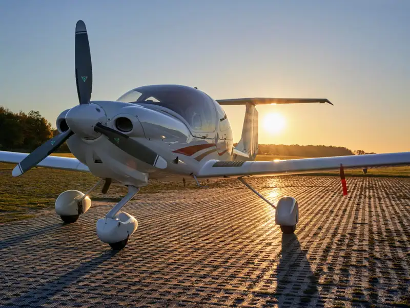 Diamond DA40 im Gegenlicht der untergehenden Sonne am Grasflugplatz